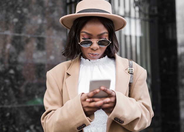 Frau mit Hut, der auf ihrem Telefon schaut