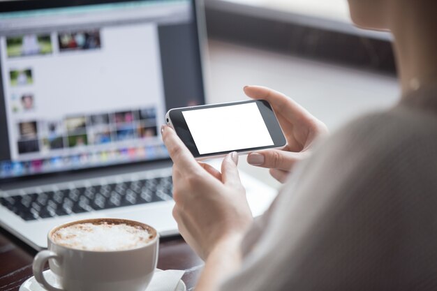 Frau mit ihrem Handy im Coffee-Shop sitzen