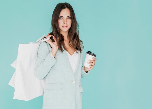 Frau mit Kaffee und Einkaufstüten auf der Schulter