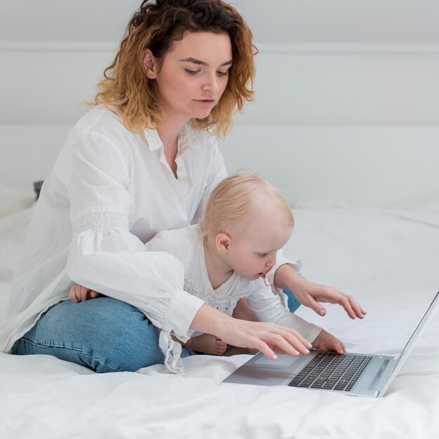 Frau mit Kind, das im Bett arbeitet