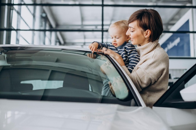 Frau mit kleinem Sohn, die ein Auto in einem Autosalon auswählt