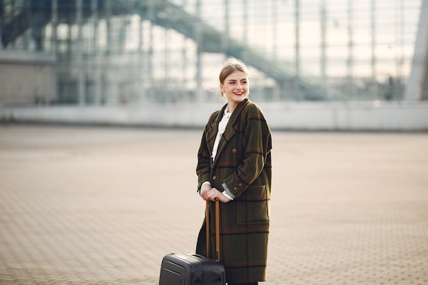 Kostenloses Foto frau mit koffer, der durch den flughafen steht