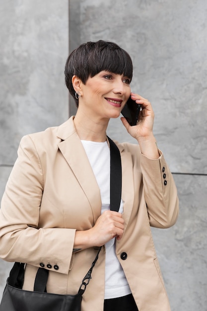 Frau mit kurzen Haaren, die draußen telefoniert