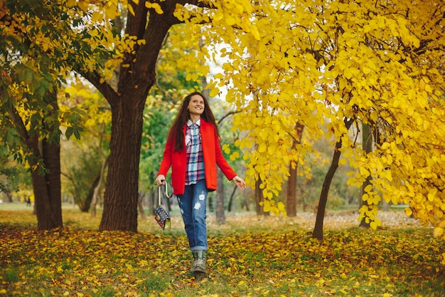 Frau mit langen gewellten Haaren, die den Herbst im Park genießen.