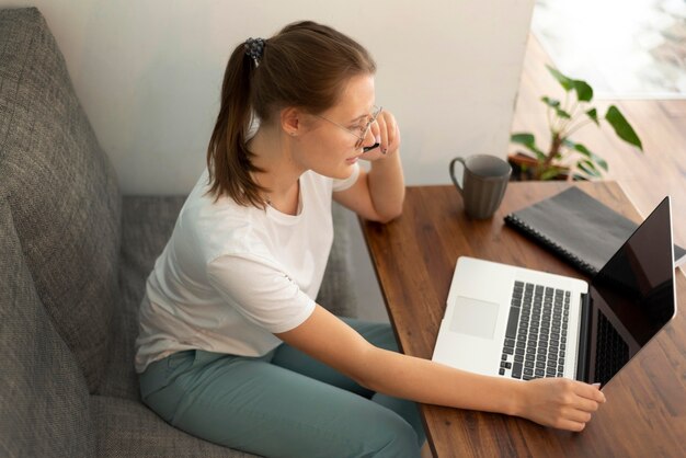 Frau mit Laptop, der von zu Hause während der Quarantäne arbeitet