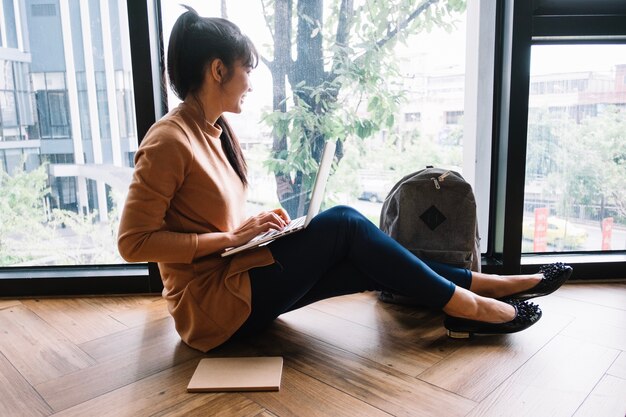 Frau mit Laptop schaut aus dem Fenster