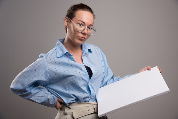 Frau mit leerer Leinwand und Pinsel auf grauem Hintergrund