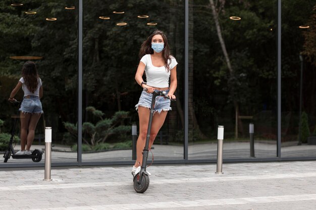 Frau mit Maske, die einen Elektroroller reitet