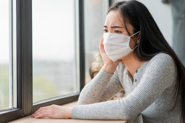 Frau mit Maske, die Fenster betrachtet