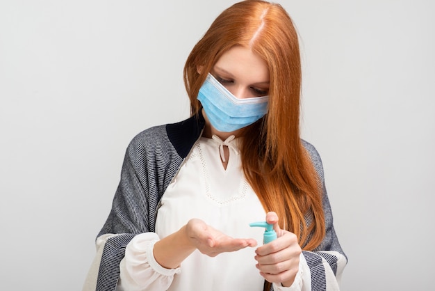 Frau mit Maske, die ihre Hände desinfiziert