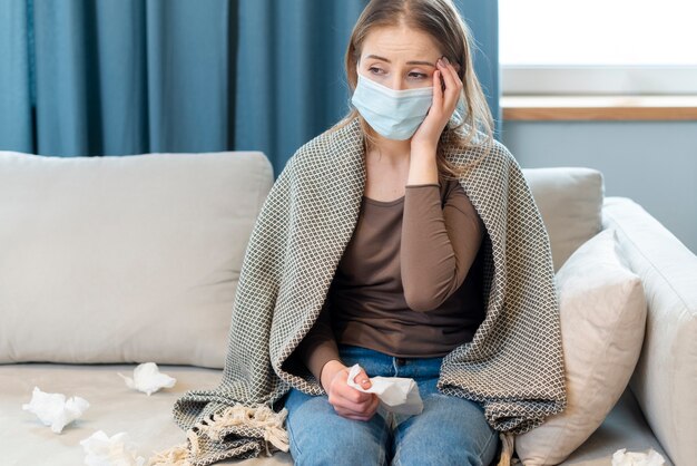 Frau mit Maske, die in der Quarantäne bleibt und Fieber hat