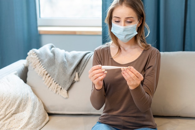 Frau mit Maske, die in Quarantäne auf einer Couch bleibt