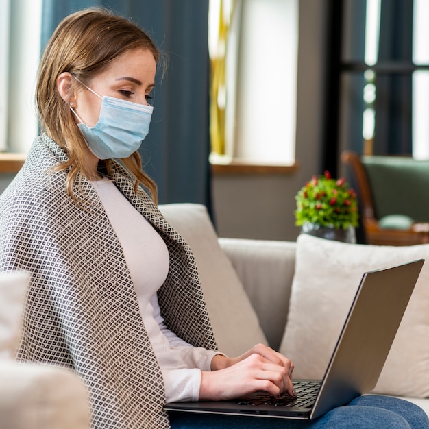 Frau mit Maske, die von zu Hause aus arbeitet