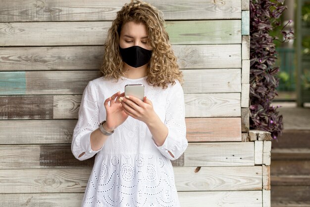 Frau mit Maske mit Handy