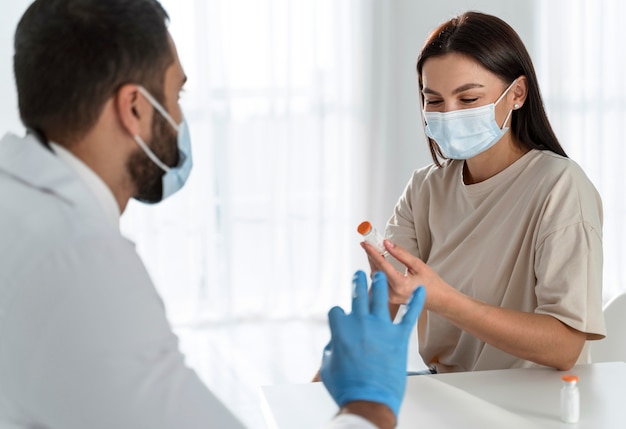 Frau mit medizinischer Maske, die mit dem Arzt spricht