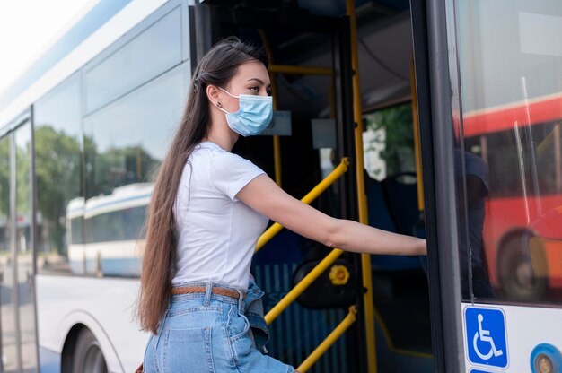 Frau mit medizinischer Maske, die öffentlichen Bus für den Transport nutzt