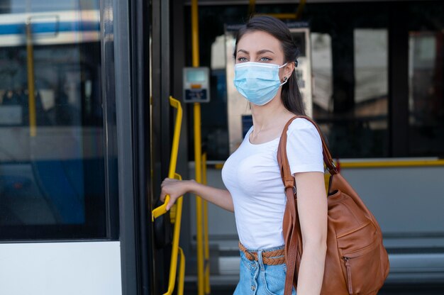 Frau mit medizinischer Maske, die öffentlichen Bus für den Transport nutzt