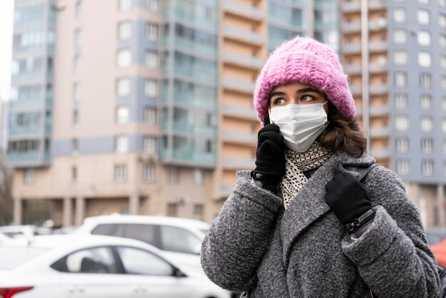 Frau mit medizinischer Maske in der Stadt, die über das Telefon spricht