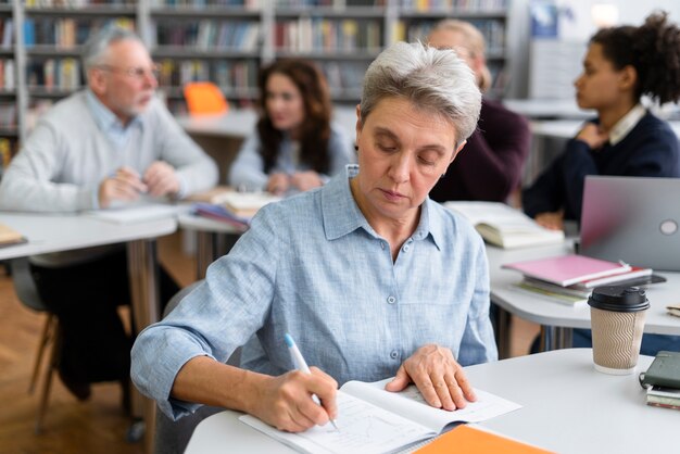 Frau mit mittlerem Schuss, die auf Notizbuch schreibt