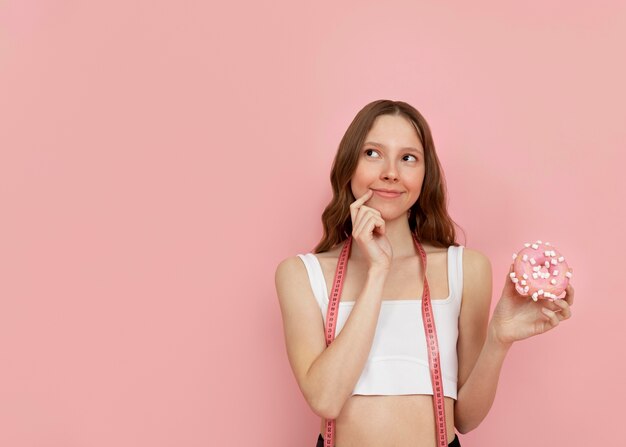 Frau mit mittlerem Schuss, die Donut hält