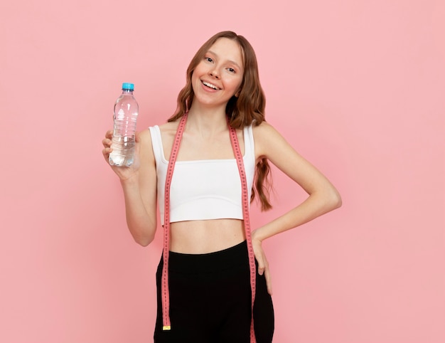 Frau mit mittlerem Schuss, die eine Wasserflasche hält