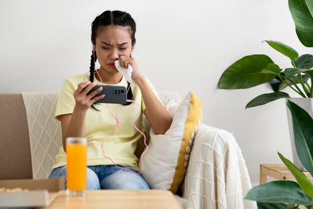 Frau mit mittlerem Schuss, die einen Film am Telefon ansieht