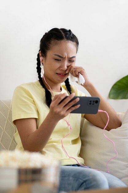 Frau mit mittlerem Schuss, die einen Film am Telefon ansieht