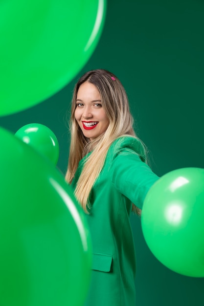 Frau mit mittlerem Schuss, die grüne Luftballons hält