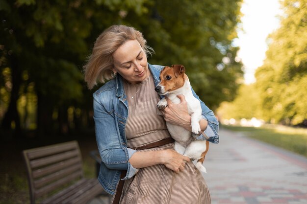 Frau mit mittlerem Schuss, die Hund hält