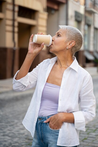 Frau mit mittlerem Schuss, die Kaffee trinkt