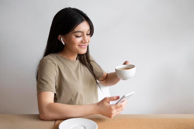 Frau mit mittlerem Schuss, die Kaffeetasse hält