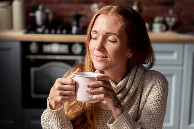 Frau mit mittlerem Schuss, die Kaffeetasse hält