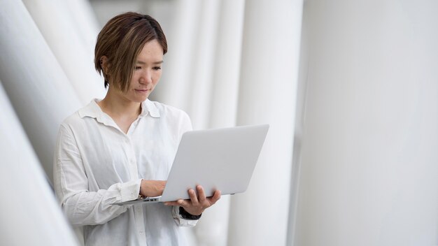 Frau mit mittlerem Schuss, die Laptop hält