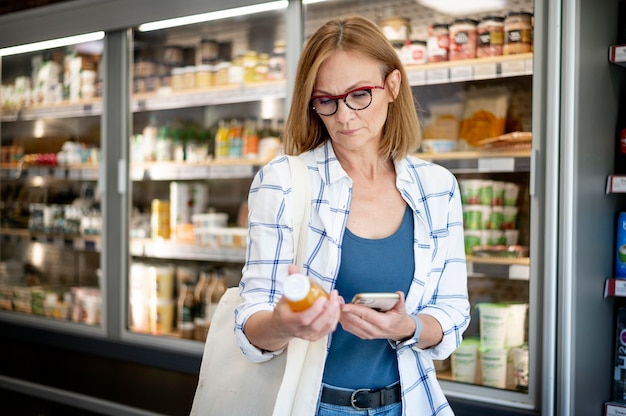 Frau mit mittlerem Schuss, die Produkt überprüft