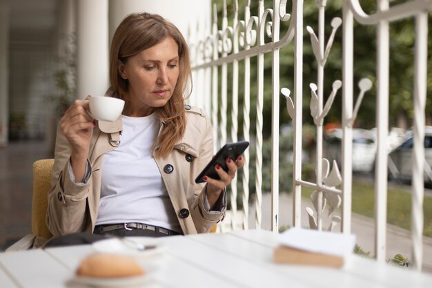 Frau mit mittlerem Schuss, die Smartphone hält