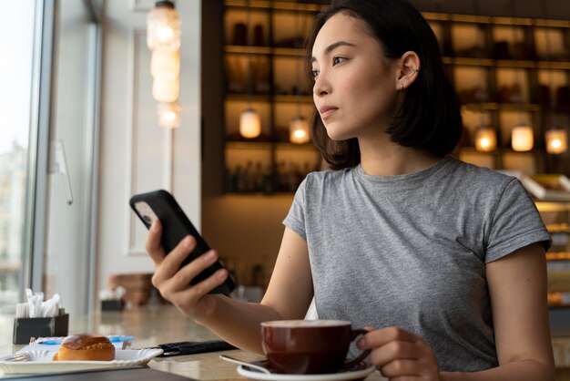 Frau mit mittlerem Schuss, die Smartphone hält