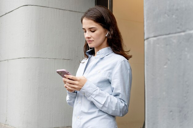 Frau mit mittlerem Schuss, die Smartphone hält