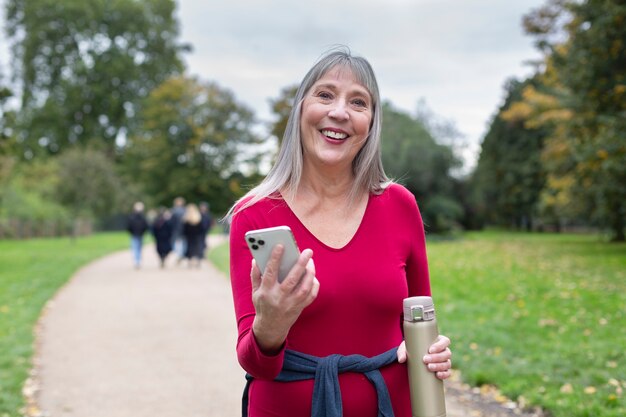 Frau mit mittlerem Schuss, die Smartphone hält