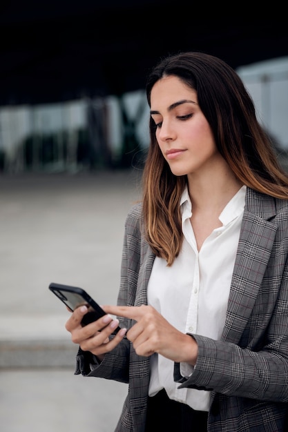 Frau mit mittlerem Schuss, die Telefon hält