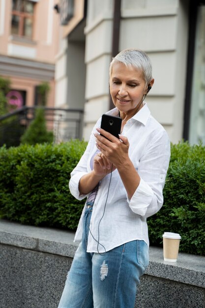 Frau mit mittlerem Schuss, die Telefon hält