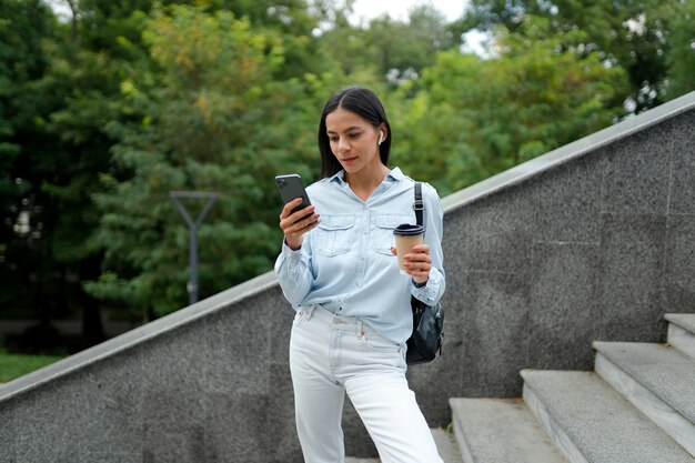 Frau mit mittlerem Schuss, die Telefon hält