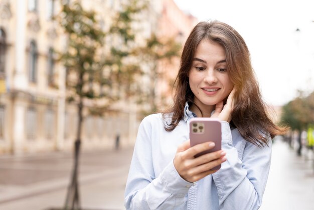 Frau mit mittlerem Schuss, die Telefon hält