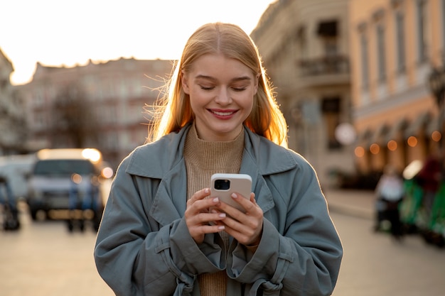 Frau mit mittlerem Schuss, die Telefon hält