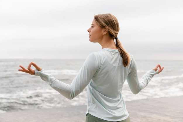 Frau mit mittlerer Aufnahme, die am Meer meditiert