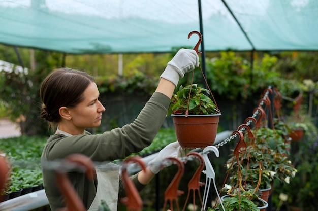 Frau mit mittlerer Aufnahme, die einen Blumentopf betrachtet