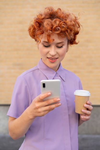 Frau mit mittlerer Aufnahme, die Telefon und Kaffee hält