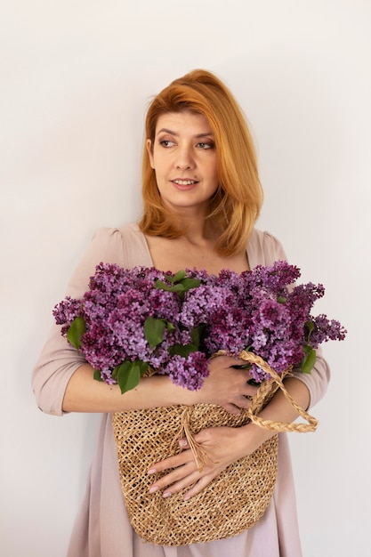 Frau mit mittlerer Aufnahme posiert mit Blumenkorb