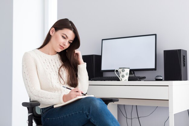 Frau mit Notizblock am Computer