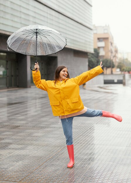 Frau mit Regenschirm, der in der Regenvorderansicht steht