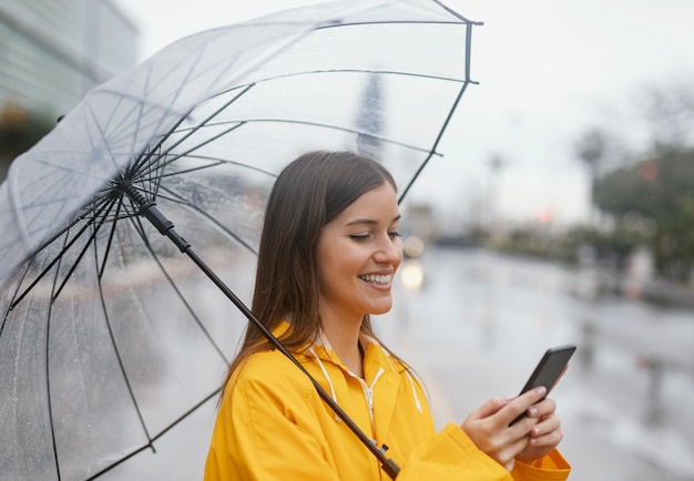 Frau mit Regenschirm mit dem Handy